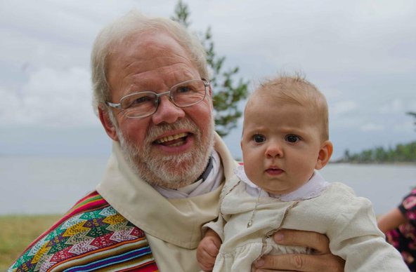 En man i glasögon med ett nydöpt barn